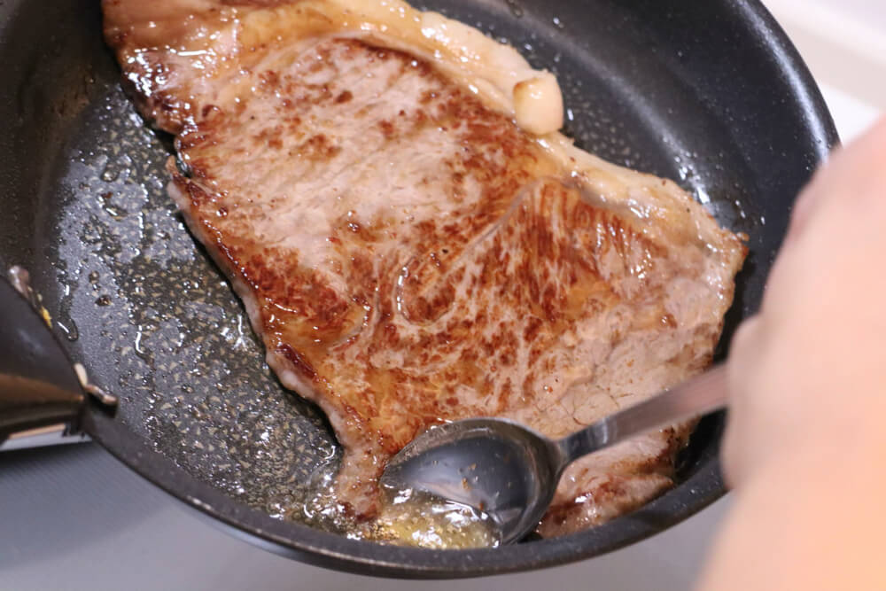 ステーキを焼く最後の仕上げは油をかけて火をとおす